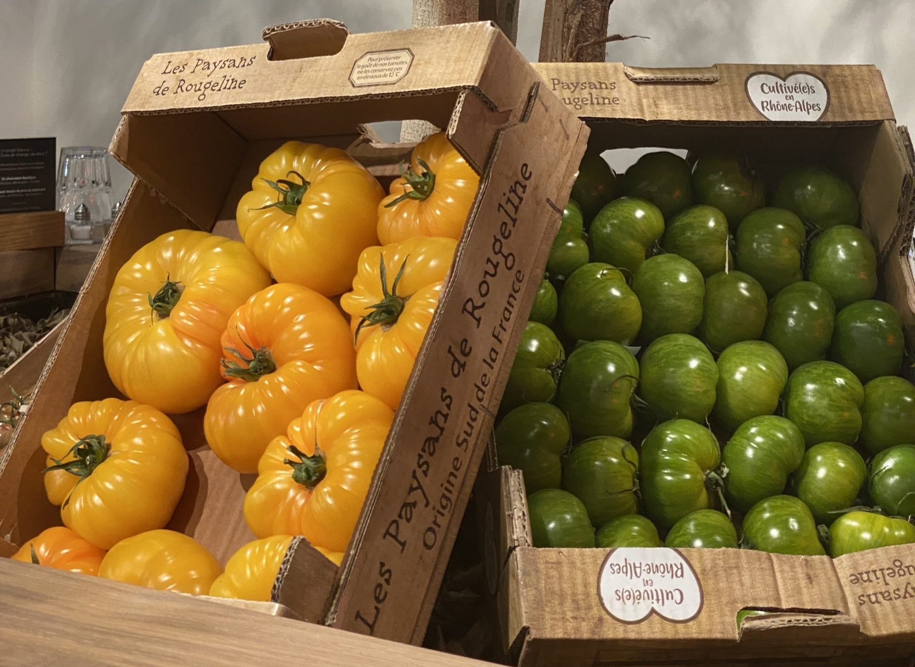 Deux boîtes de tomates vertes et jaunes sur une table